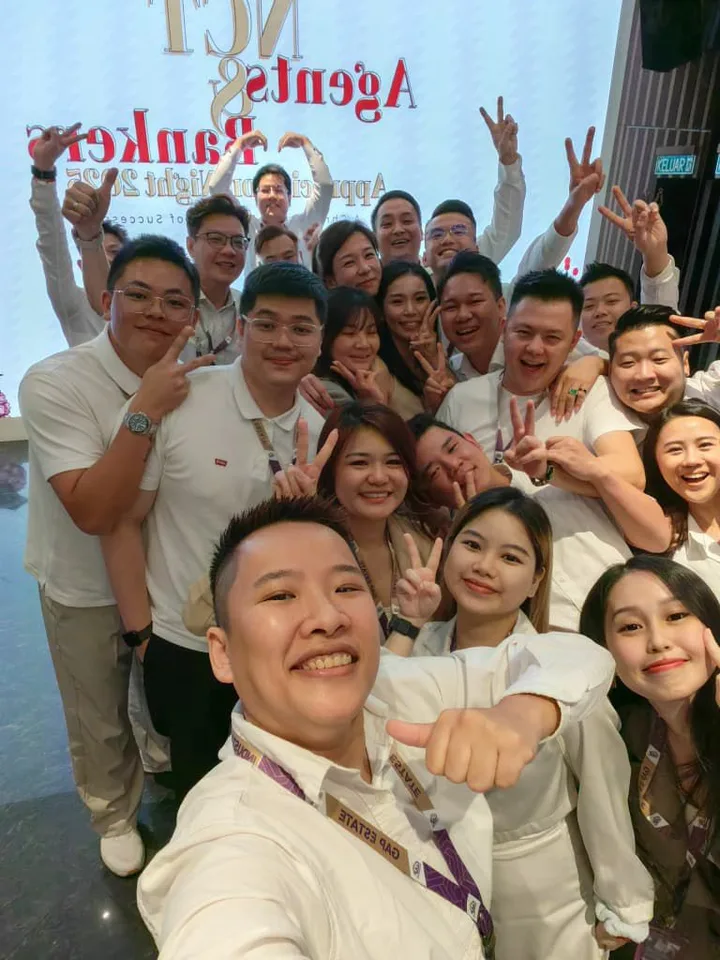 A large group leaning together for a selfie at an indoor event.